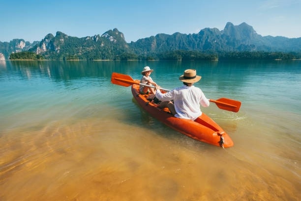 Mother and son floating on kayak together on Cheow Lan lake in Thailand