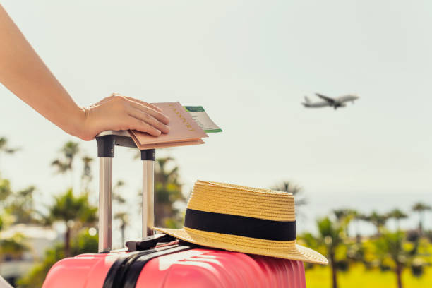 Woman with pink suitcase and passport with boarding pass